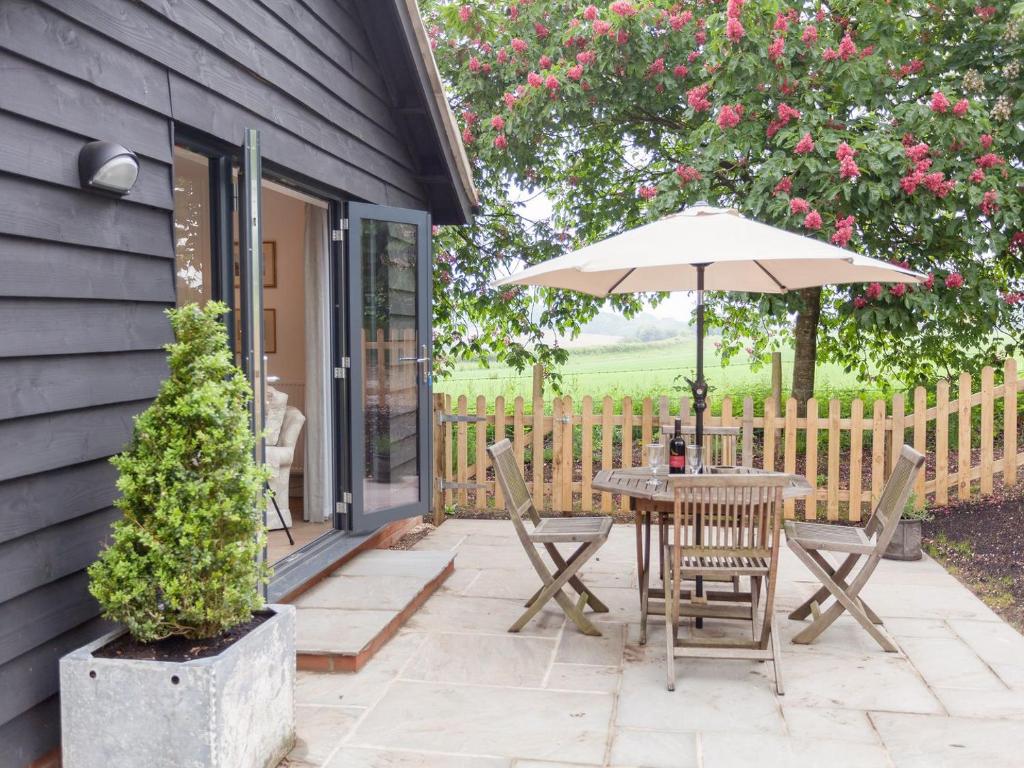 a patio with a table and chairs and an umbrella at The Dairy in Cheriton