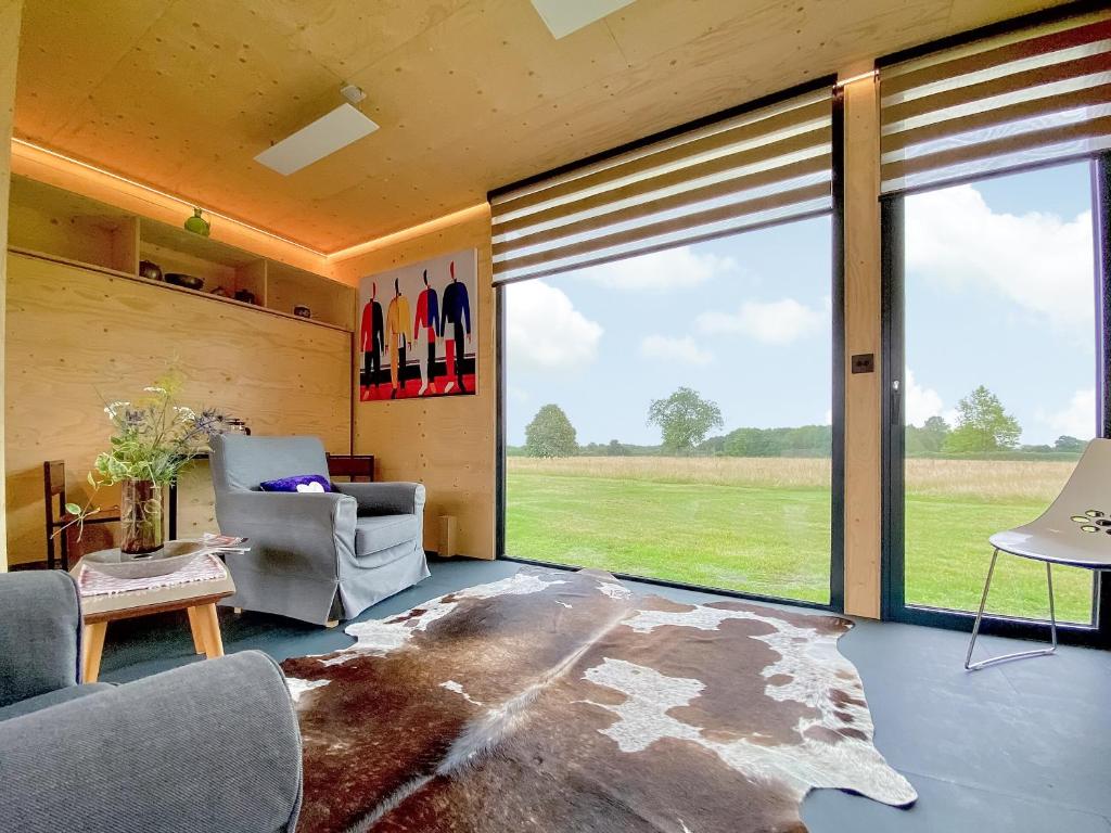 uma sala de estar com uma grande janela com vista para um campo em The Studio em Yatton Keynell