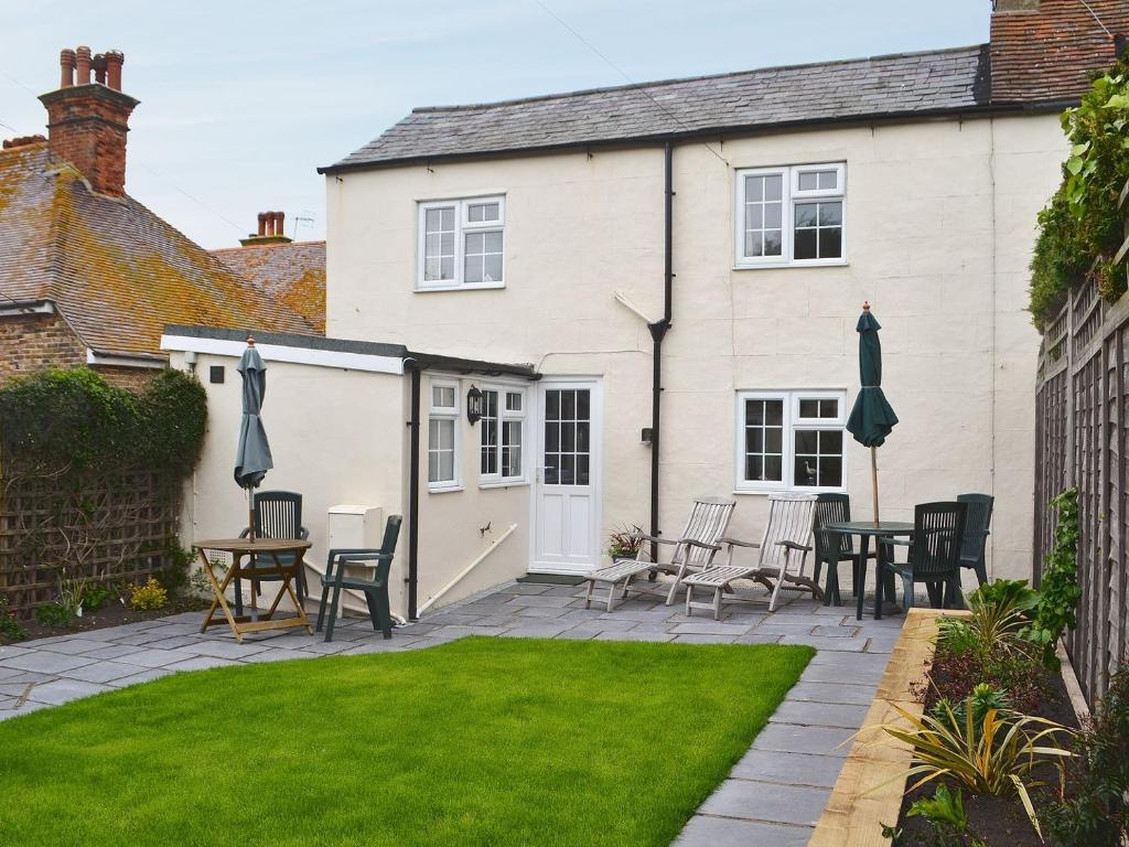a patio with chairs and tables in front of a house at Garden Cottage in Rottingdean