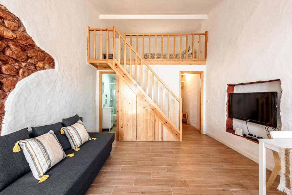 a living room with a couch and a staircase at Casa Xanoca in Vila do Bispo