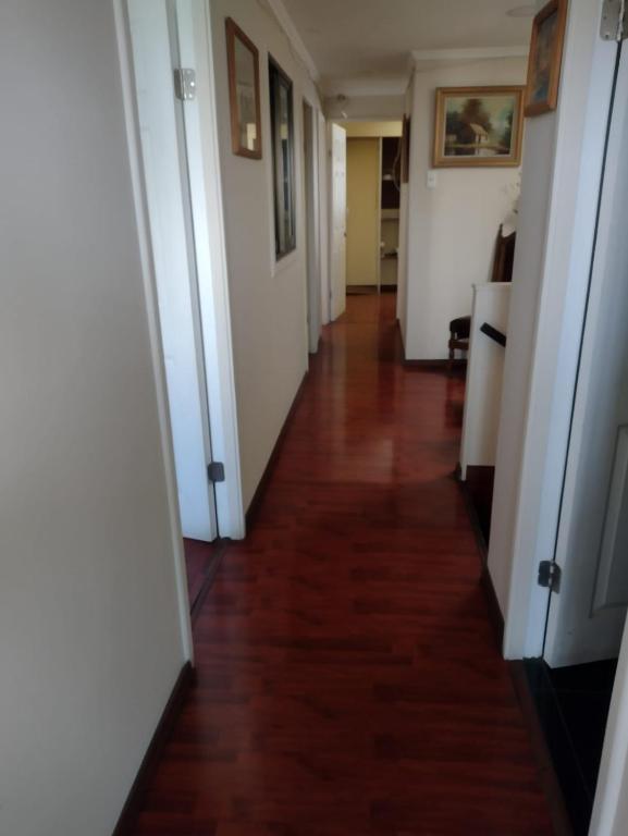 un long couloir avec des murs blancs et du parquet. dans l'établissement Hostal Ines, à Santiago