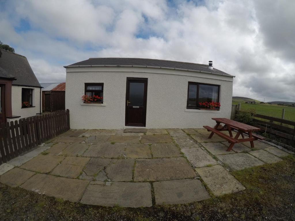 a small white building with a bench in front of it at Madras cottage Orkney Islands in Harray