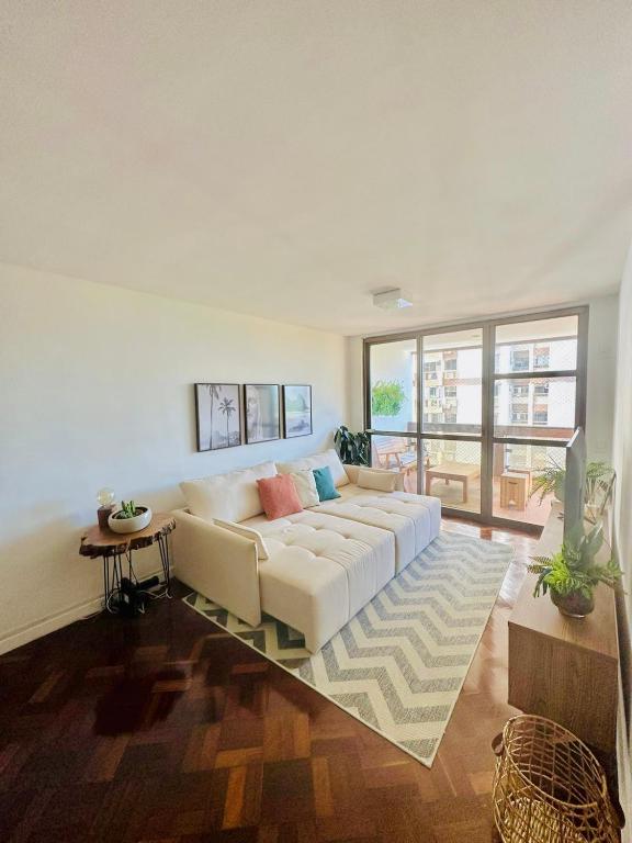 Hotel Lindo Apartamento na Praia da Barra - Amplo e Confortável!, a living room with a white couch and a table at Lindo Apartamento na Praia da Barra - Amplo e Confortável! in Rio de Janeiro
