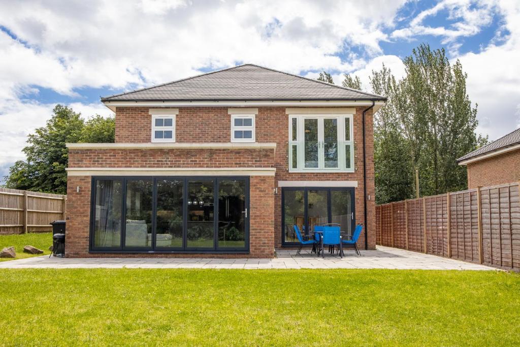 a house with glass doors on a lawn at The Orchard - Spacious 5 Bed in Burton upon Trent