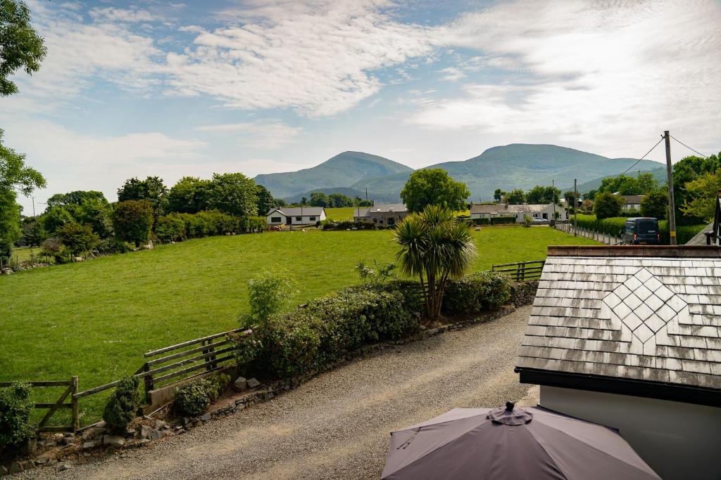a house with an umbrella and a field with mountains at The Briers Country House in Newcastle