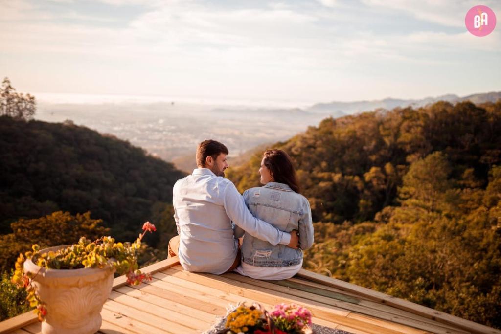 Ein Mann und eine Frau, die auf einem Deck sitzen und die Aussicht betrachten. in der Unterkunft Pousada Caminho dos Canyons in Praia Grande