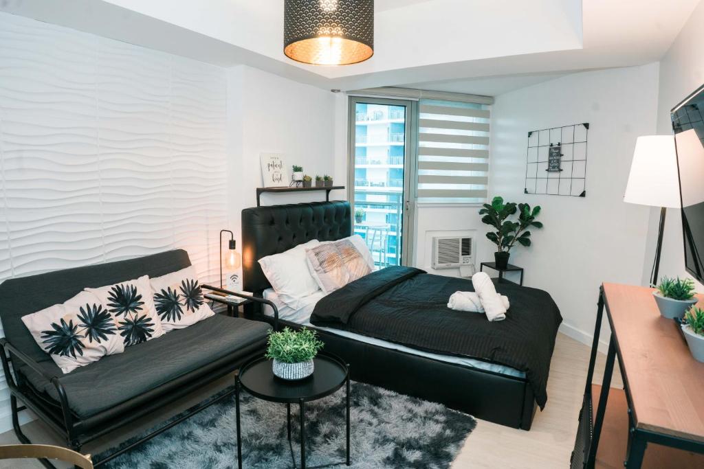 a bedroom with a black bed and a table at Resort Condo Unit with Stunning View - Azure North in Lagundi