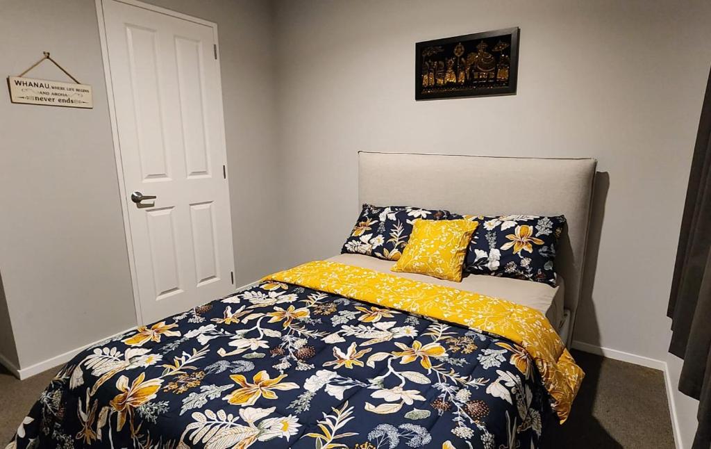 a bedroom with a bed with a blue and yellow comforter at A room in Riverstone Terraces with views - Homestay in Upper Hutt