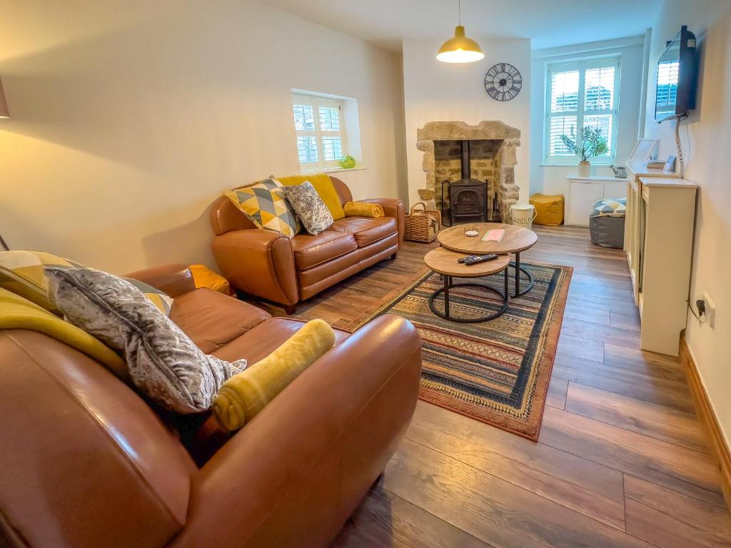 a living room with leather furniture and a fireplace at Old Hall Cottage No 1 in Byers Green