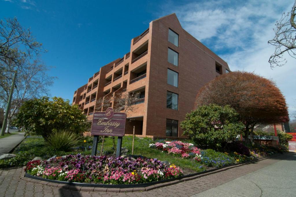 um sinal em frente a um edifício com flores em The Embassy Inn em Victoria