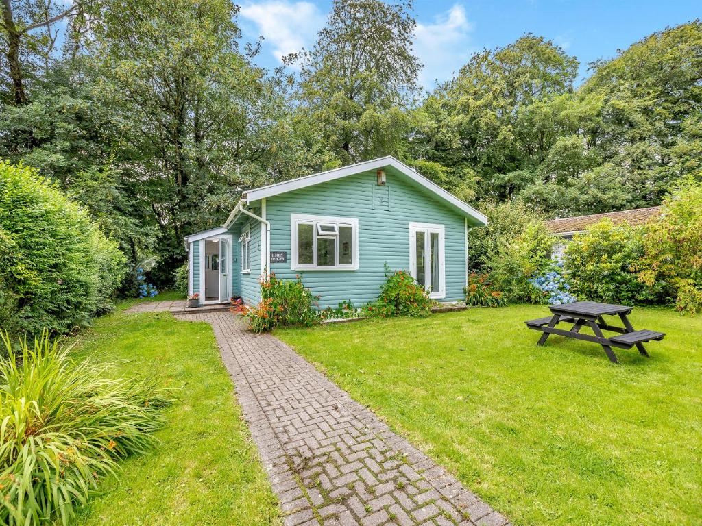 ein grünes Cottage mit einem Picknicktisch im Hof in der Unterkunft Honey Hanger - W43106 in Bradworthy