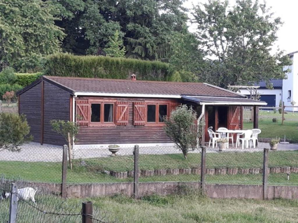 une cabane en rondins avec une table et des chaises dans une cour dans l'établissement Gîte Arpajon-sur-Cère, 3 pièces, 4 personnes - FR-1-742-21, à Arpajon-sur-Cère