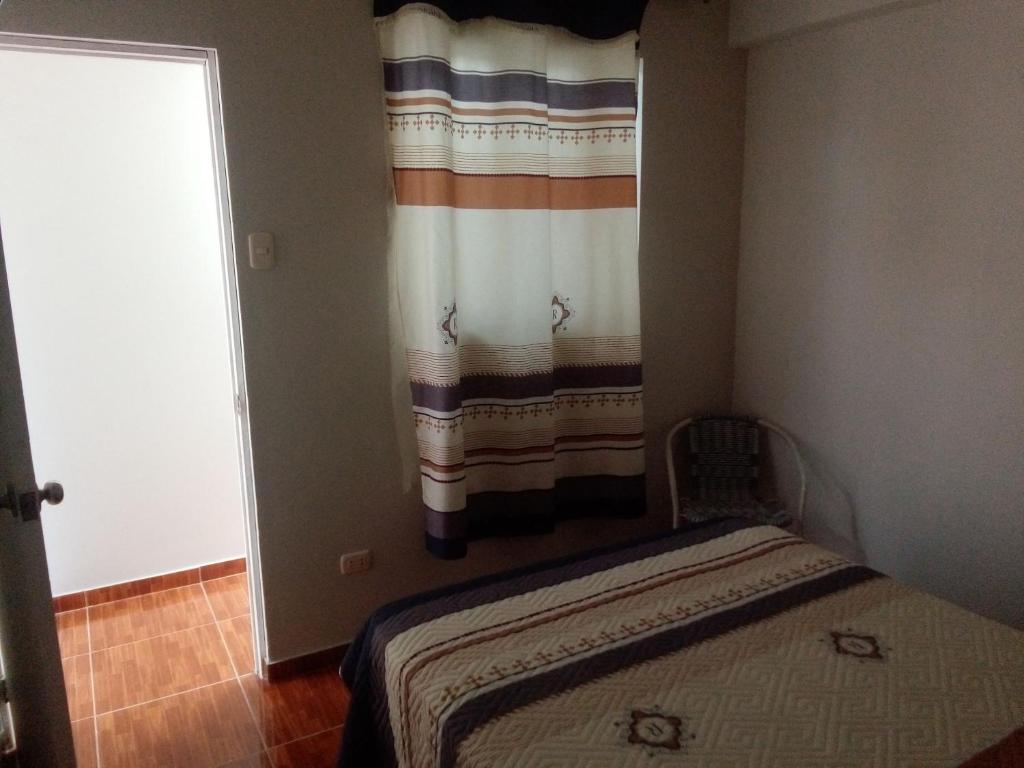 a small bedroom with a bed and a curtain at Hospedaje Vivanco 