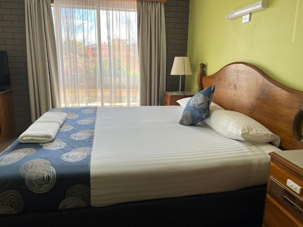 1 dormitorio con 1 cama grande y ventana en Tumut Valley Motel, en Tumut