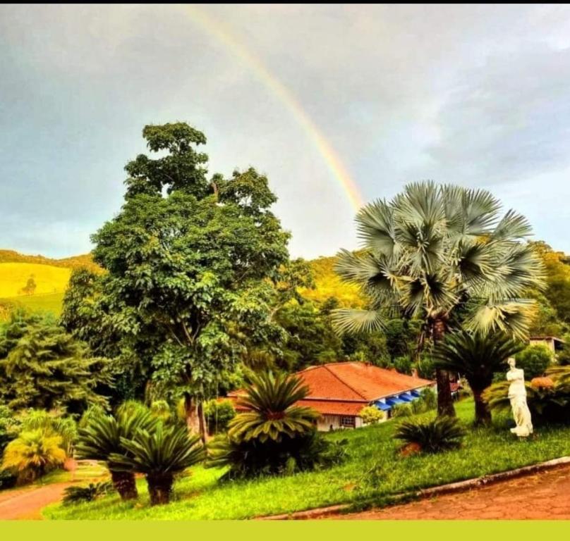 a rainbow in the sky over a house with palm trees at Pousada NAIF in São Lourenço