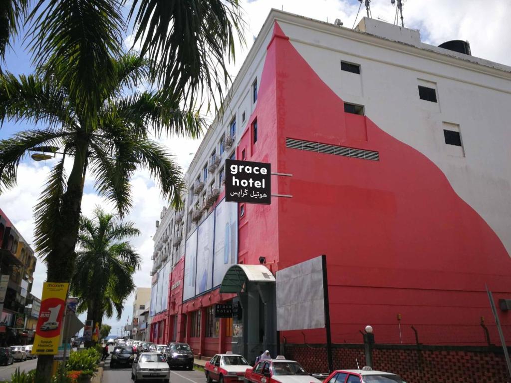ein rotes Gebäude mit einem Schild an der Seite in der Unterkunft Grace Hotel Lahad Datu in Lahad Datu