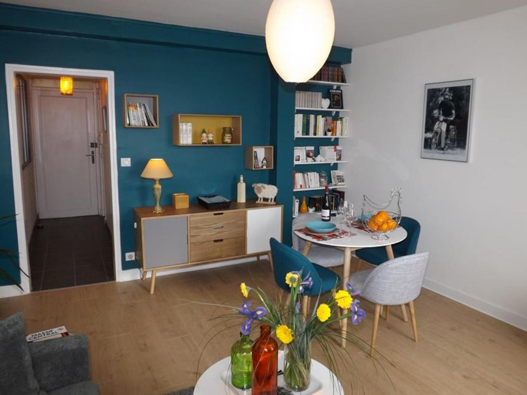 un salon avec une table et un mur bleu dans l'établissement Appartement Aurillac, 2 pièces, 2 personnes - FR-1-742-389, à Aurillac