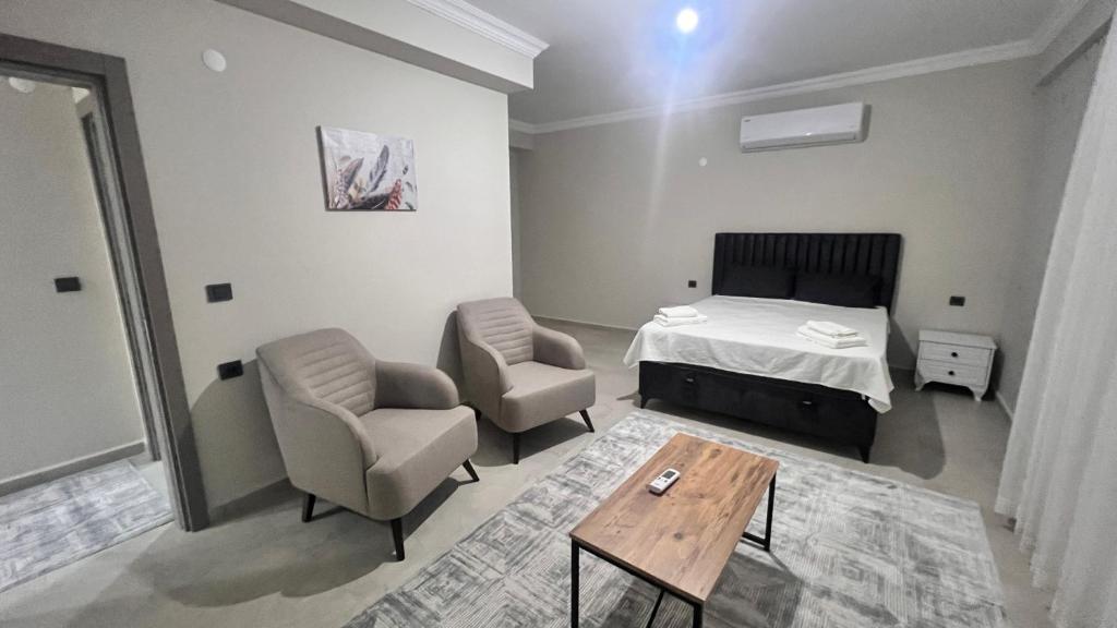 a bedroom with a bed and two chairs and a table at SELİNTİ CİTY DAİRE 1 Suit in Gazipasa