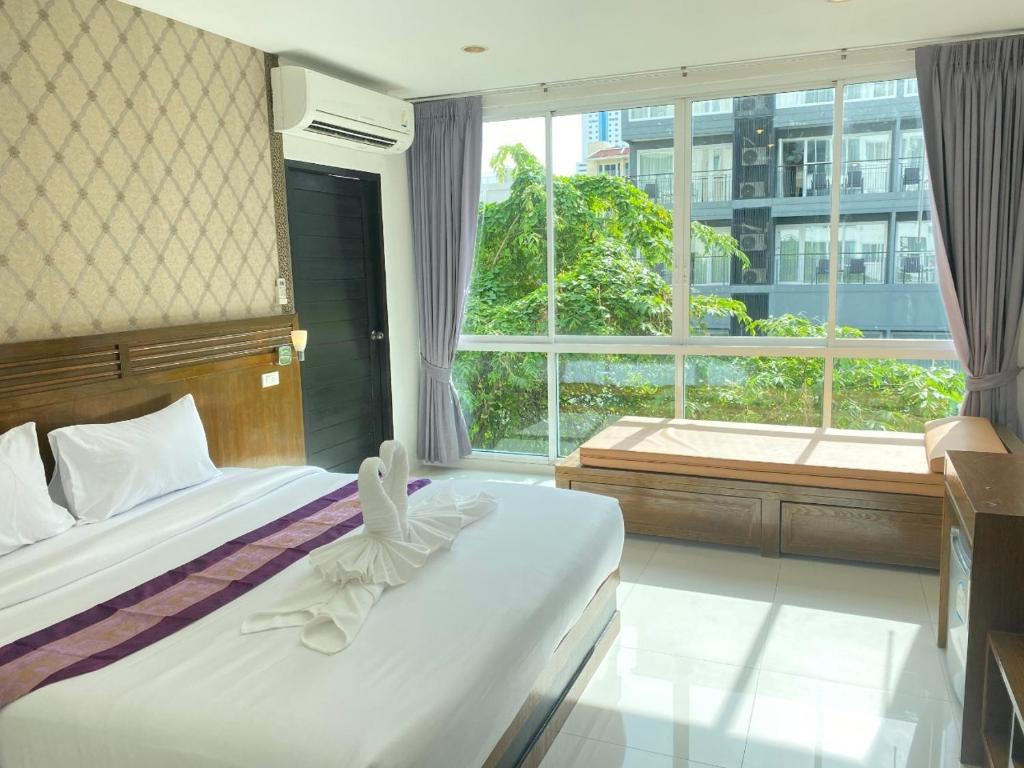 a bedroom with two beds and a large window at NJ PATONG HOTEL in Patong Beach