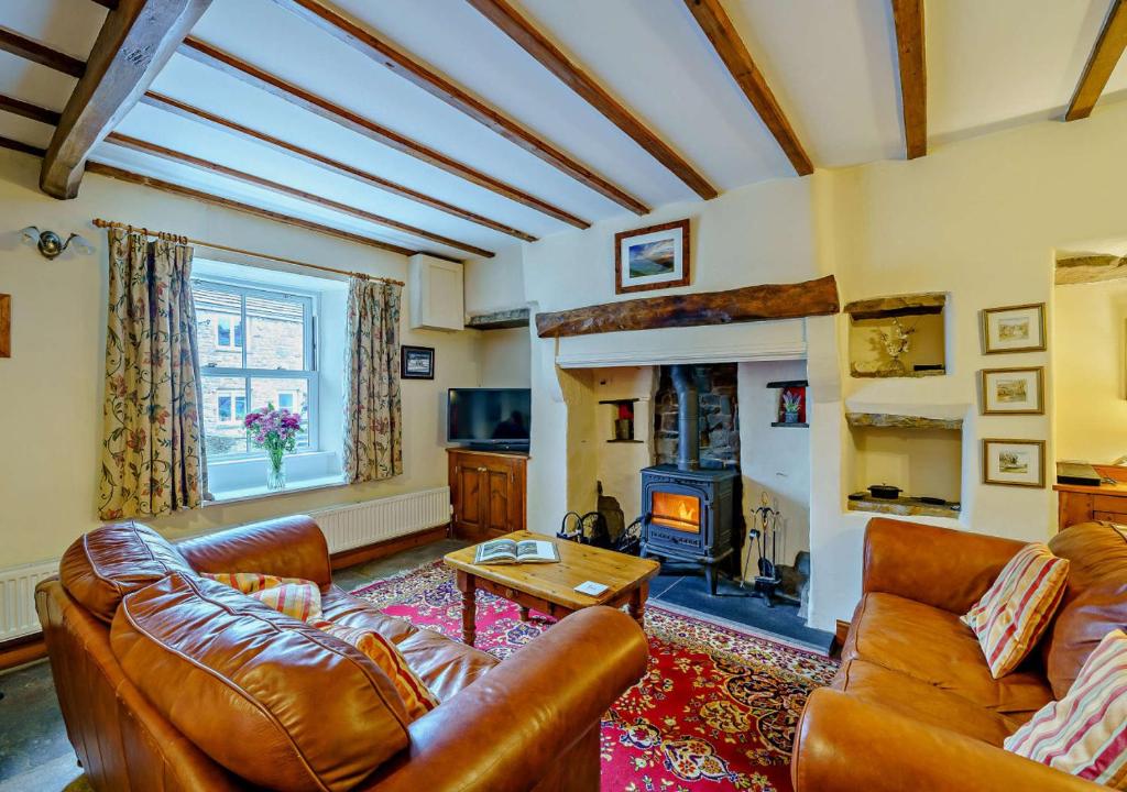 a living room with leather furniture and a fireplace at Marys Cottage in Hawes
