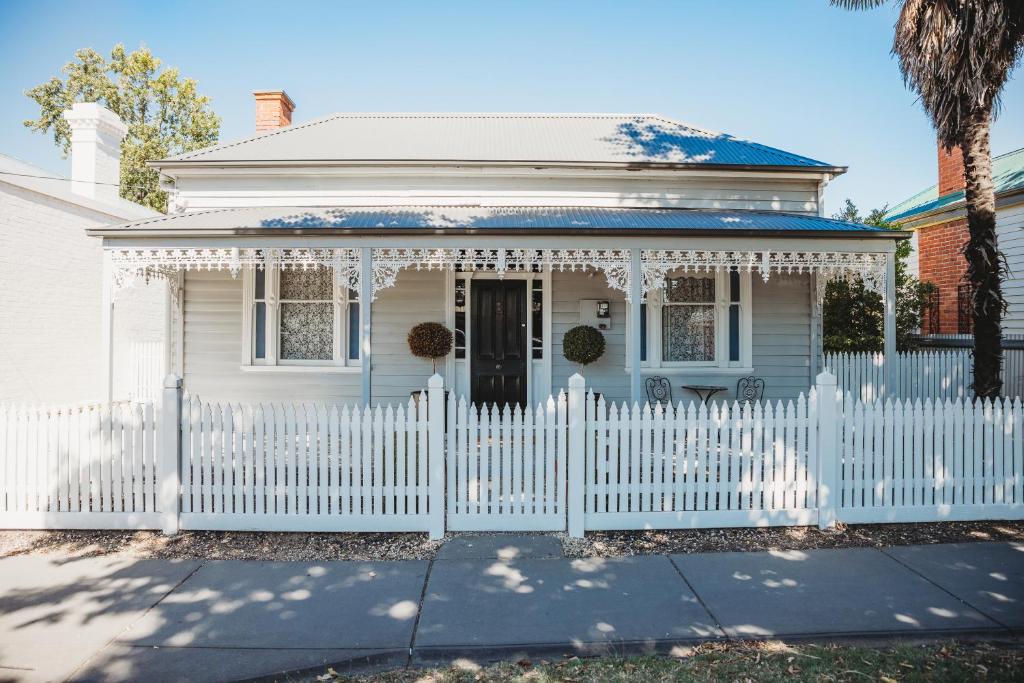 a white house with a white picket fence at Hargreaves Cottage - close to CBD in Bendigo