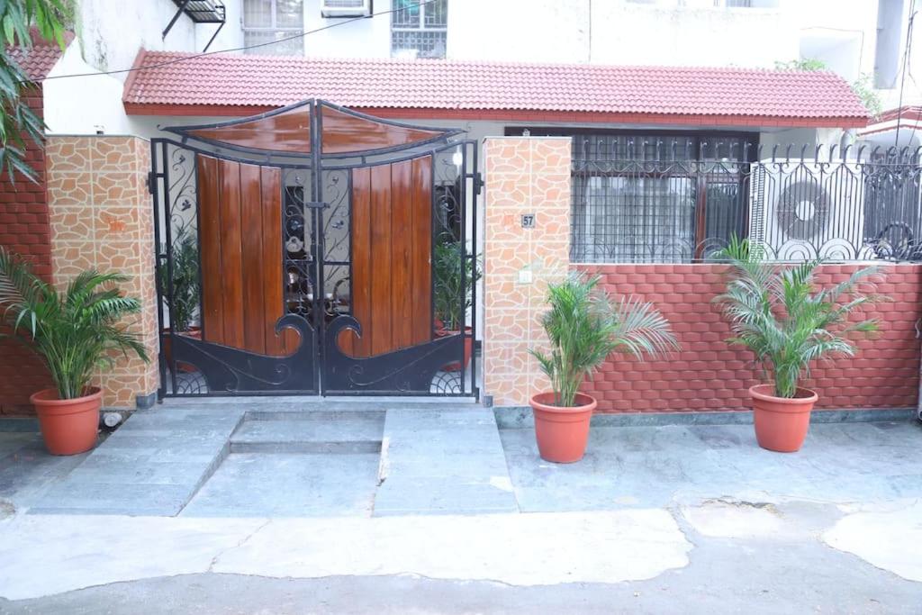 una puerta negra con dos macetas delante de una casa en Divine India Service Apartment 3Bhk,B57 Sarita Vihar,Apollo en Nueva Delhi