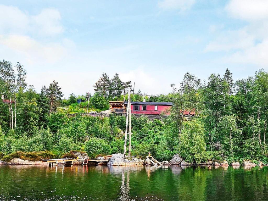 uma casa vermelha no topo de uma colina ao lado de um lago em Holiday home lyngdal IX em Lyngdal