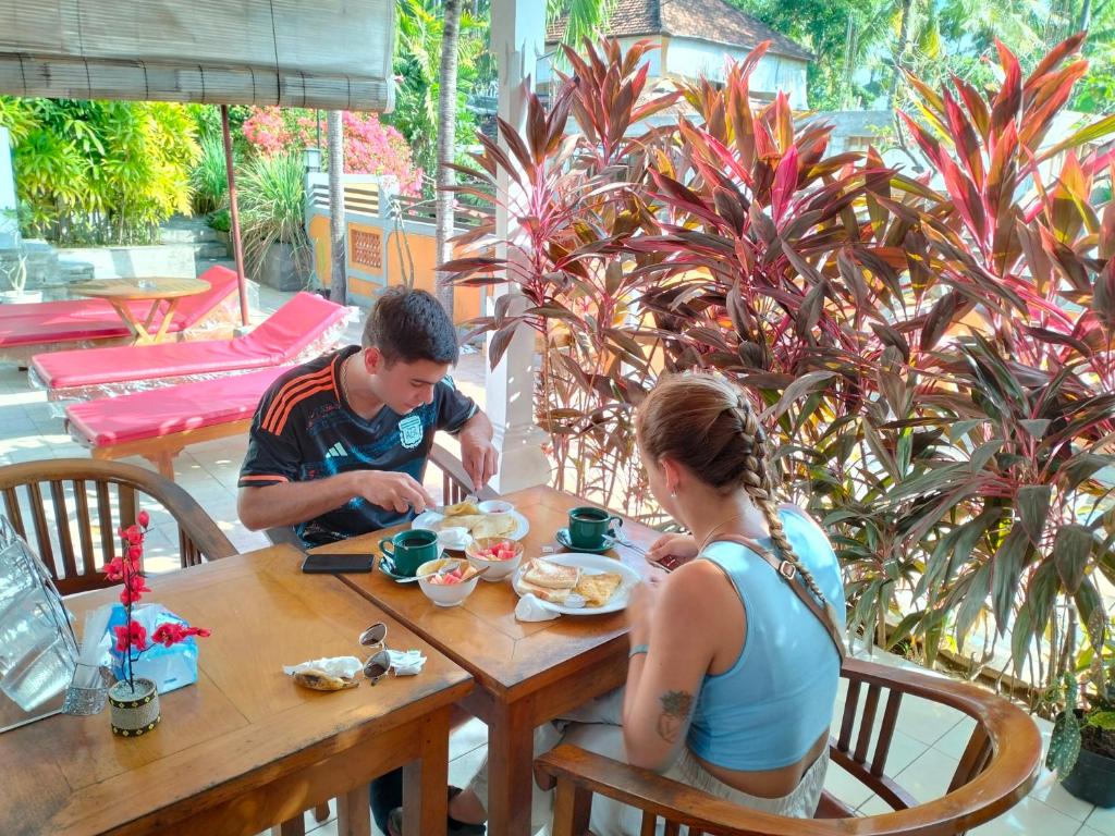 un homme et une femme assis à une table dans l'établissement Kaia Lovina Guest House, à Lovina