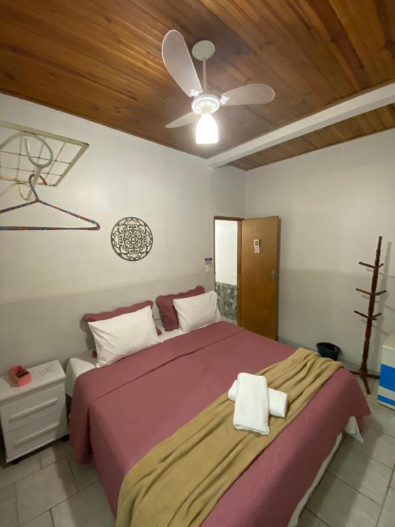 a bedroom with a large bed with a ceiling fan at Pousada Recanto da Vila in Pirenópolis