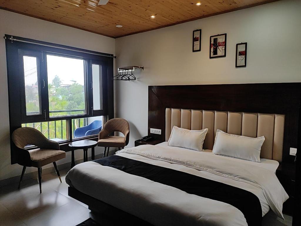a bedroom with a large bed and two chairs at StudioZ Paradise Hills Mussoorie in Mussoorie