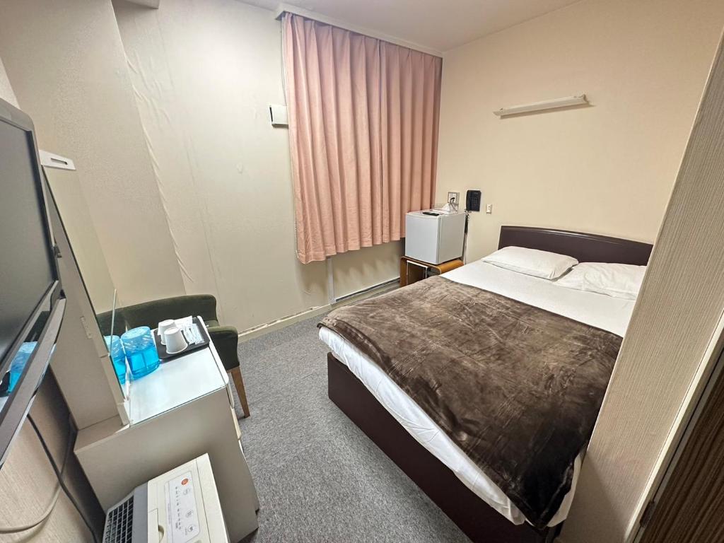 a hotel room with a bed and a television at City Villa Rアネックス in Osaka