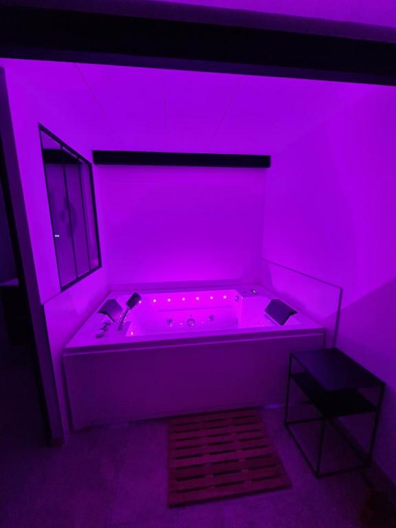 Habitación púrpura con bañera en una habitación con mesa en Gîte spa la parenthèse en Sauve