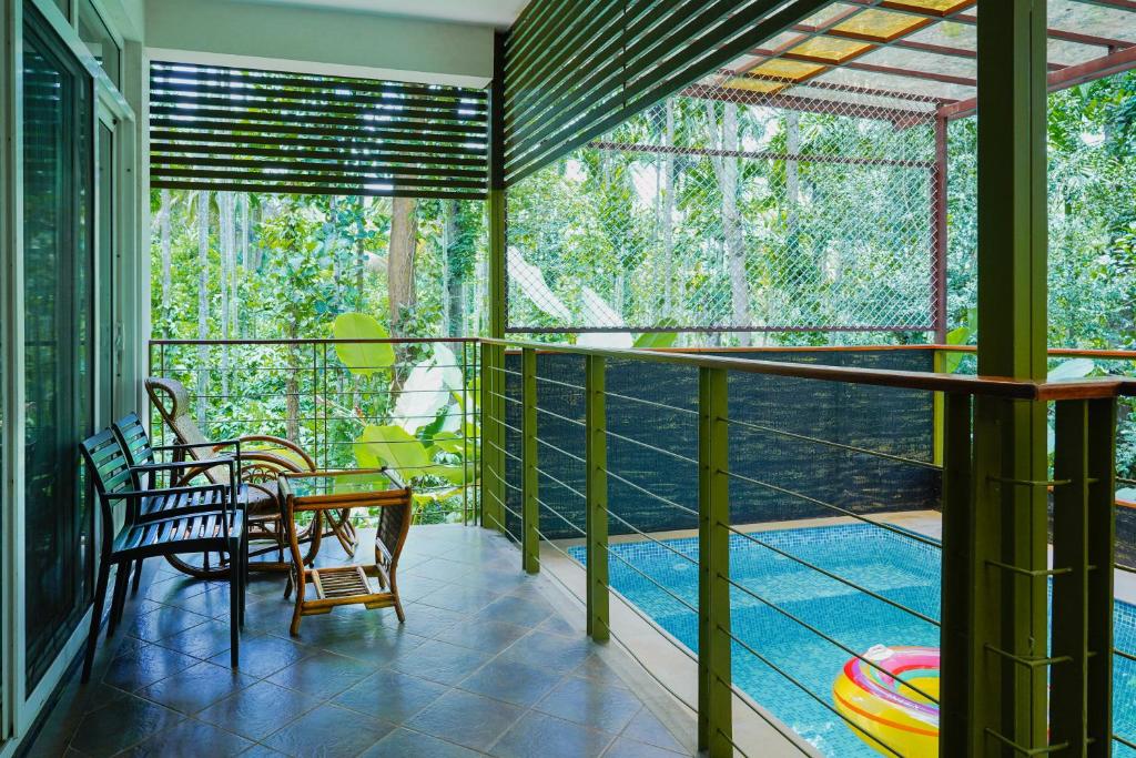 a room with a balcony with a table and chairs at Kuruva Island Resort And Spa - By KABINI BREEZE, Wayanad in Mananthavady