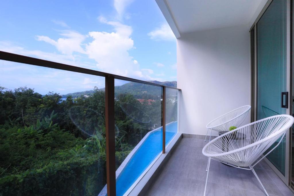 a balcony with chairs and a view of the mountains at Oceana Phuket in Kamala Beach