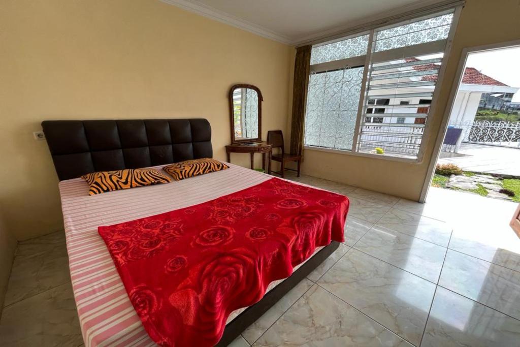a bedroom with a large bed with a red blanket at OYO LIFE 92844 Penginapan Cibodas in Pasuruan