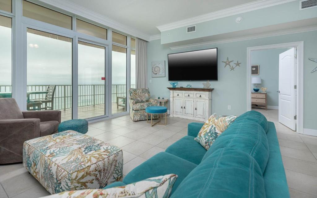 een woonkamer met een blauwe bank en een flatscreen-tv bij Phoenix Orange Beach II 1105 condo in Orange Beach