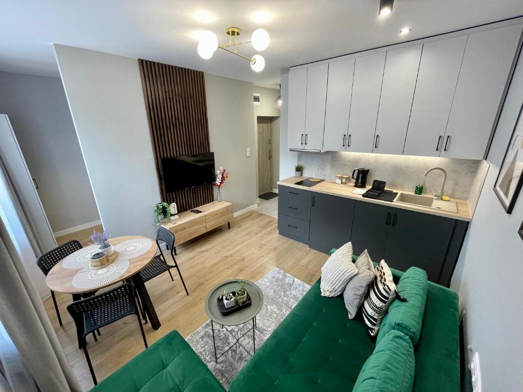 a living room with a green couch and a kitchen at Przytulny apartament niedaleko dworca PKP in Radom