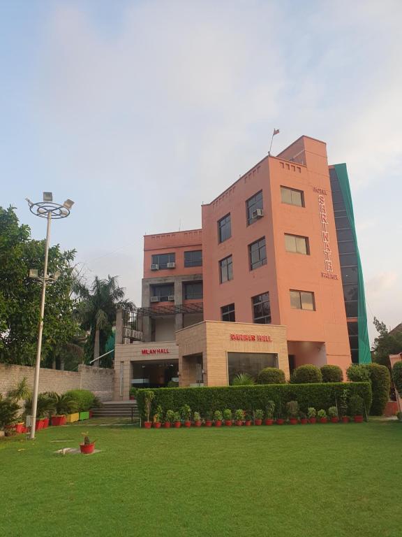 a building with a green lawn in front of it at Hotel Shrinath Palace in Jhānsi