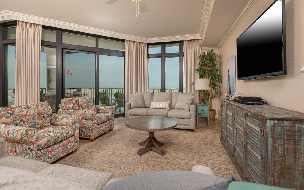 a living room with a couch and a tv at The Oasis 2214 formerly Phoenix West II 2214 in Orange Beach