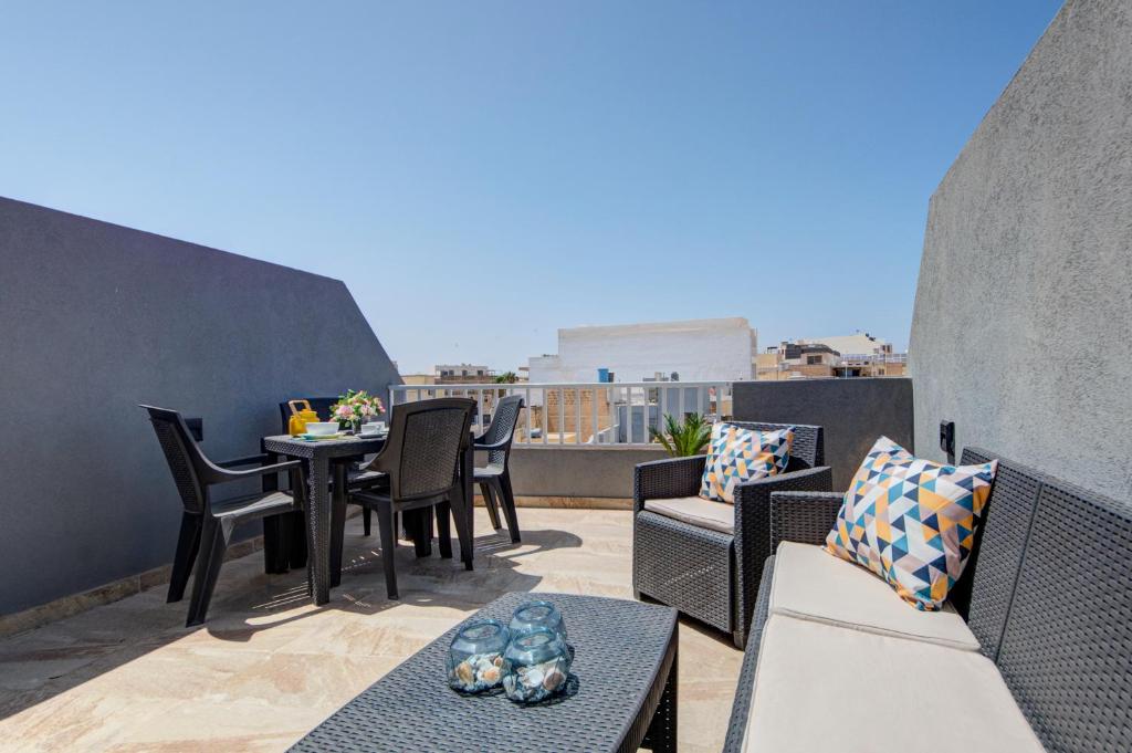 d'une terrasse avec une table et des chaises sur un balcon. dans l'établissement Few minutes from Valletta modern 2-bd roof top apartment, à Marsa