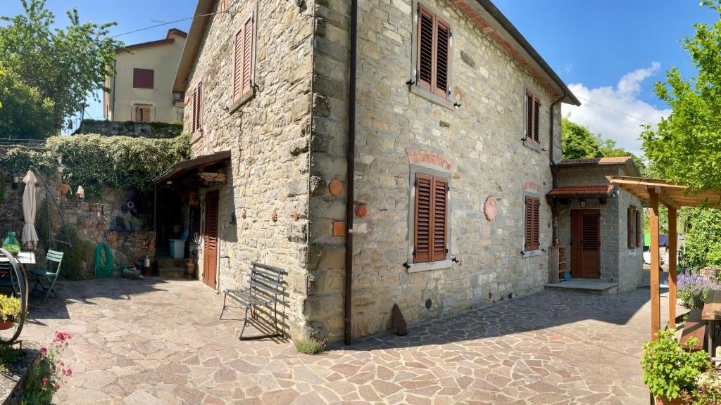 - un grand bâtiment en pierre avec une terrasse en face dans l'établissement Villa Elisabetta, à Chiusi della Verna