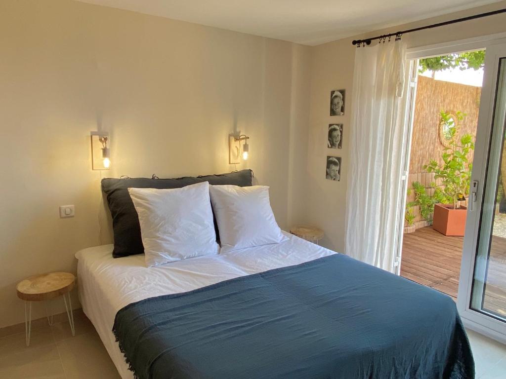 um quarto com uma cama com um cobertor azul e uma janela em L'Arbousier em Rayol-Canadel-sur-Mer