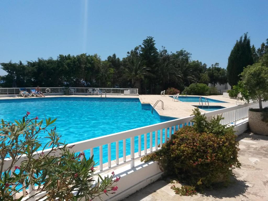 een groot zwembad met een wit hek eromheen bij Ikaria Village Apt 201 in Paphos City