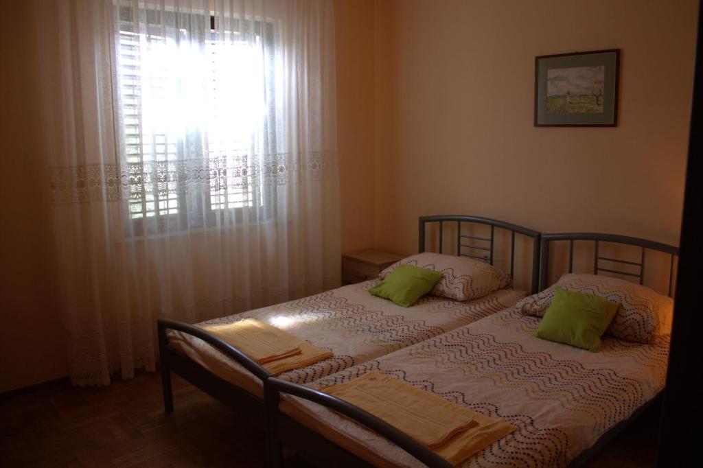 een slaapkamer met een bed met groene kussens en een raam bij Apartma SUZY in Koper