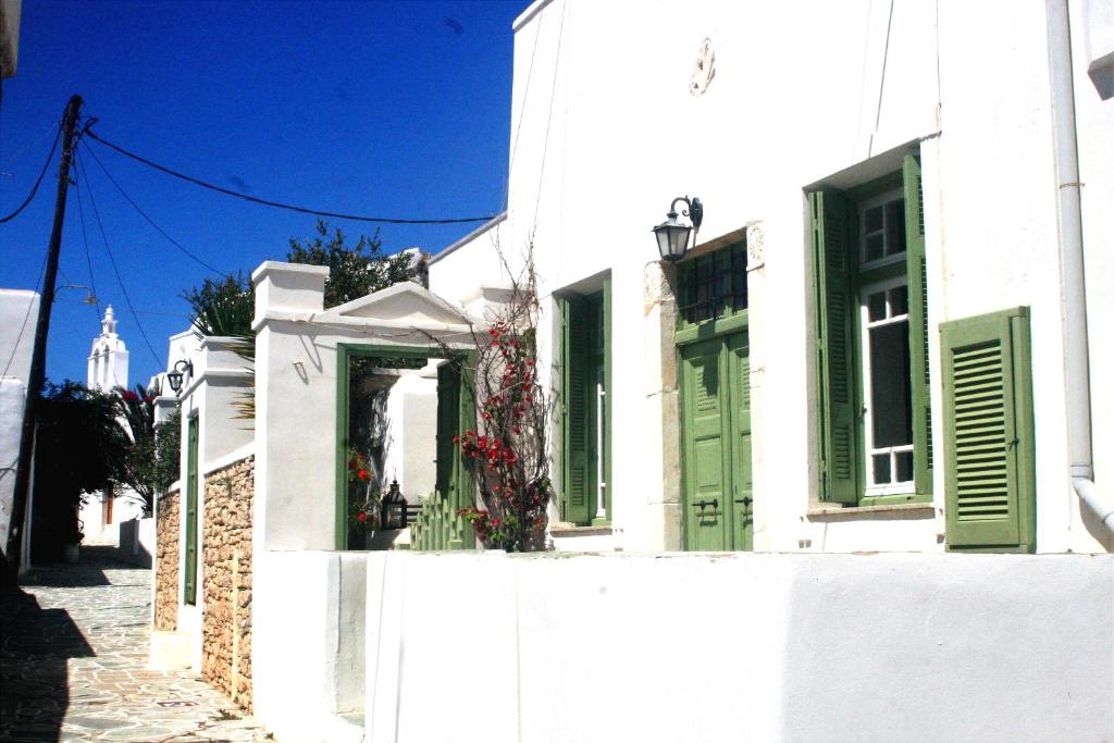 un bâtiment blanc avec volets verts dans une rue dans l'établissement Matsas Mansions, à Folégandros