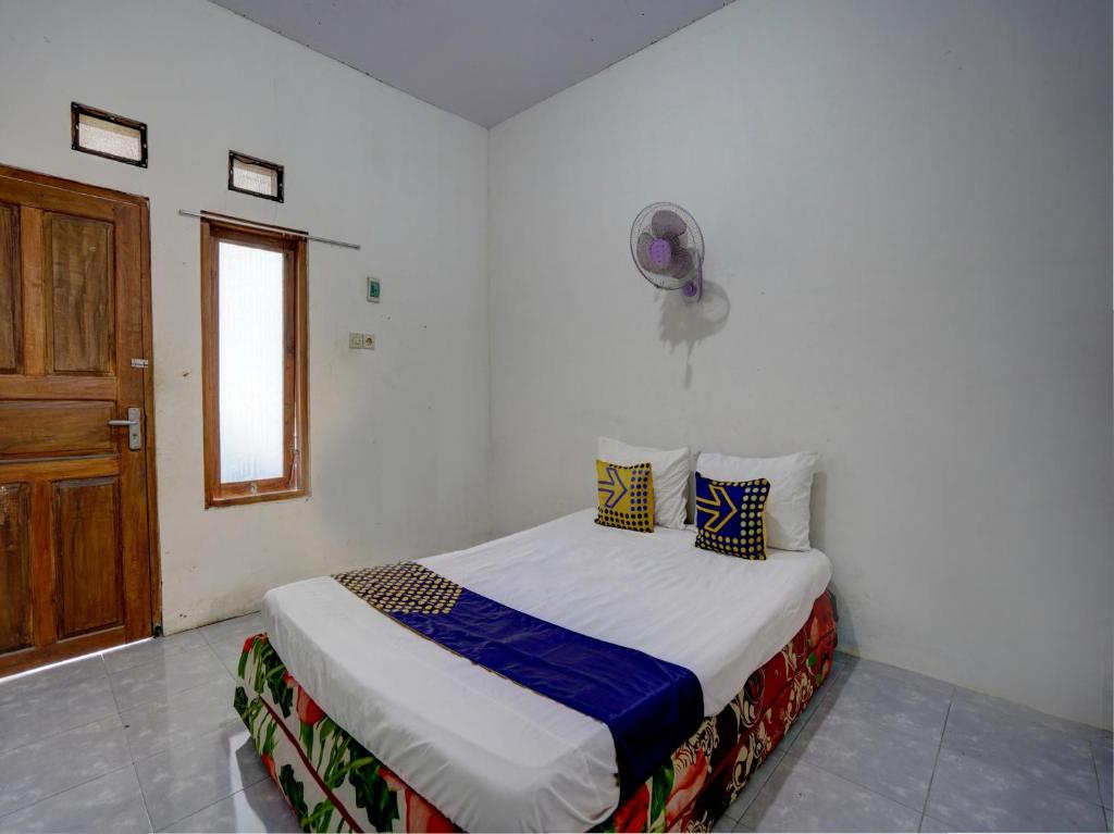 sypialnia z łóżkiem w białym pokoju w obiekcie SPOT ON 92855 Griya Sandi Syariah Rogojampi w mieście Banyuwangi