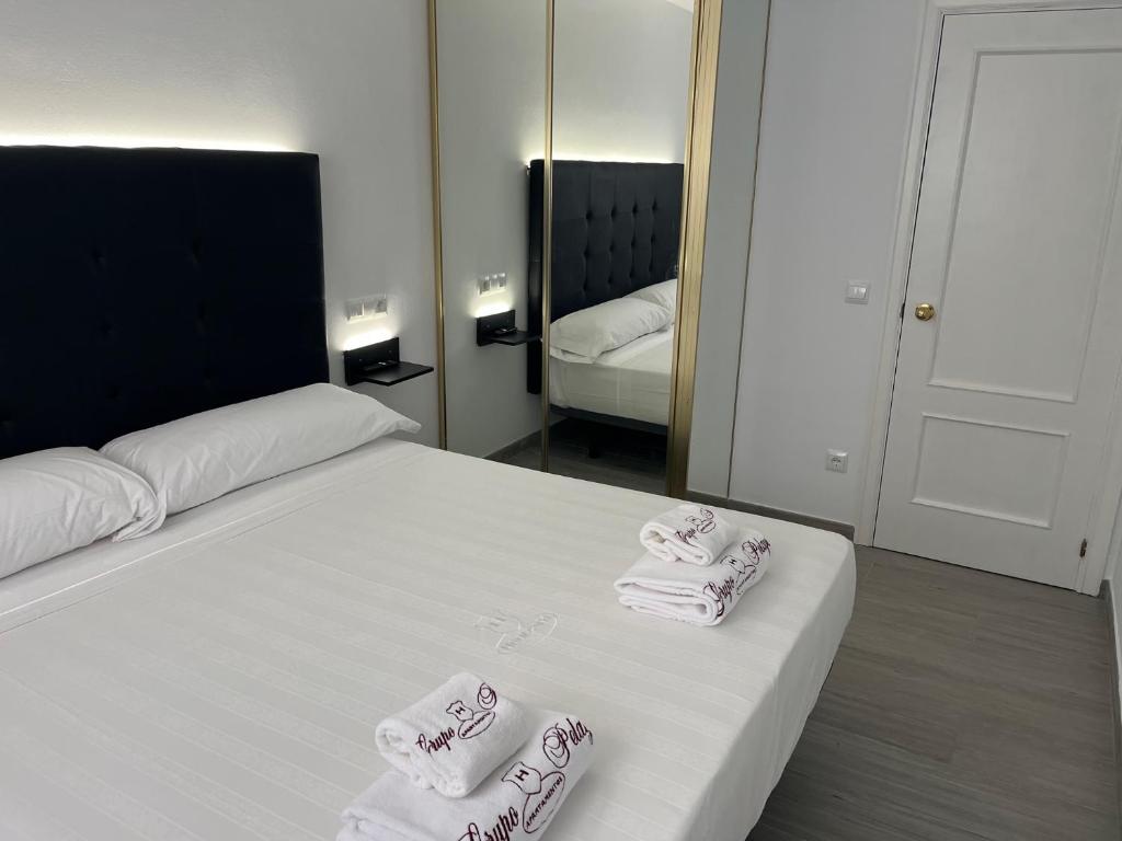 a bedroom with a white bed with towels on it at H Pelayo Auto Check-In Rooms in Noja