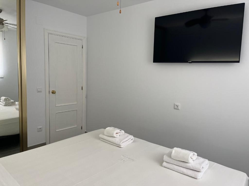 a white bed with two towels on top of it at H Pelayo Auto Check-In Rooms in Noja