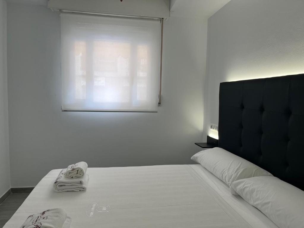 a bedroom with a bed with white sheets and a window at H Pelayo Auto Check-In Rooms in Noja