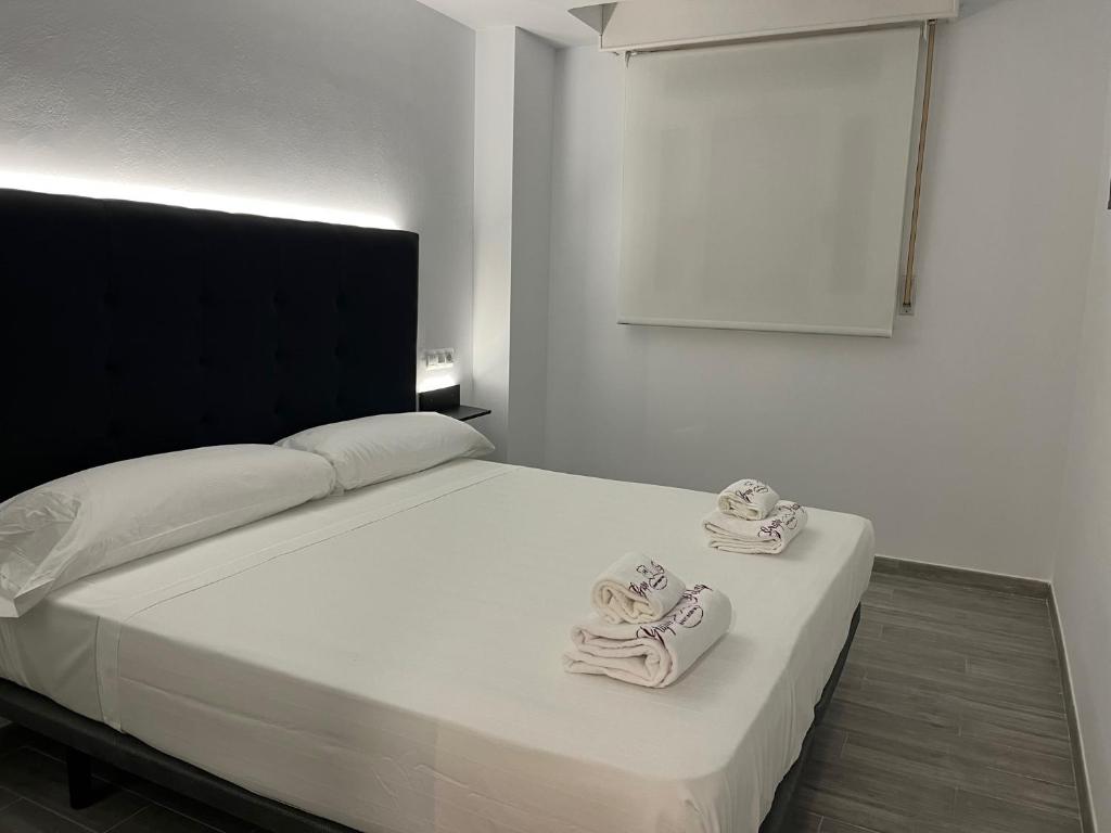 a bedroom with a white bed with towels on it at H Pelayo Auto Check-In Rooms in Noja